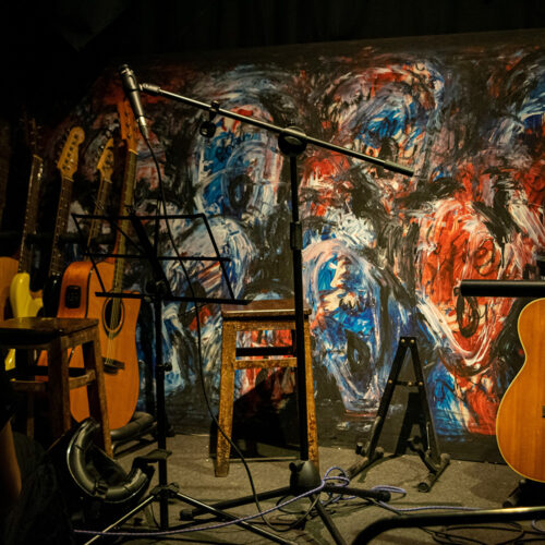 microphone on stage with art as backdrop and guitars